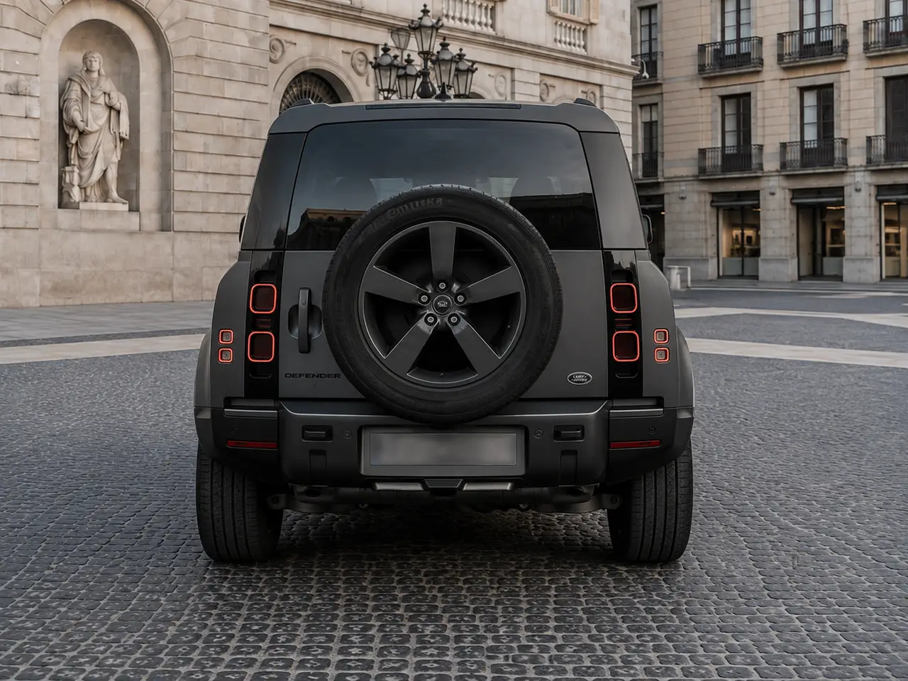 Land Rover Defender 2024, rear view — Barcelona Luxury Car Rental, Barcelona. The 2024 Land Rover Defender in this fleet carries 400 hp and seats seven, which puts it…